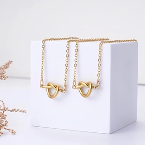 Primer plano detallado de un collar con colgante de nudo de corazón en tono dorado
