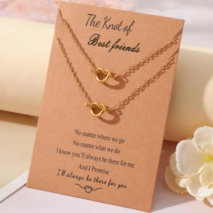Detail of two gold heart knot pendant necklaces on a Best Friends gift card
