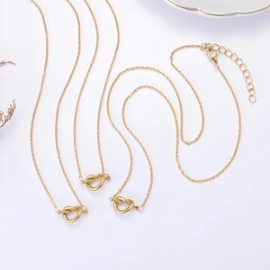 Tres collares dorados con nudos en forma de corazón sobre fondo blanco con flores