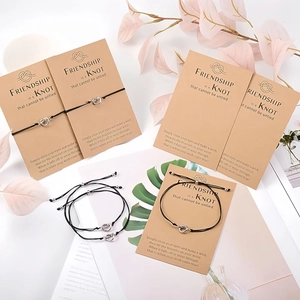 Set of five handmade black braided friendship bracelets with heart knots on kraft cards