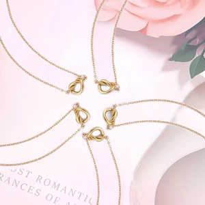 Detalle de cinco collares con colgante de nudo dorado sobre un fondo floral