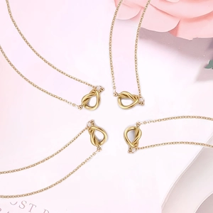 Vista detallada de cuatro collares con colgante de nudo de amor dorado y fondo floral