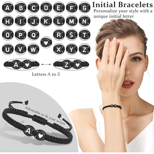 Macro-detail van verstelbare zwarte geweven armband met witte hart- en letterbedeltjes