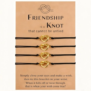 Detail of four handmade knotted friendship bracelets with gold heart charms on gift card
