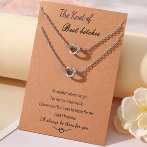Detail view of two knot heart necklaces on brown gift card with white floral decor