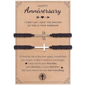 Detail of couple cross bracelets on a vintage kraft paper anniversary gift card