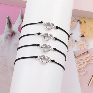 Detail of four handmade knot bracelets with black cords on a white cylindrical display