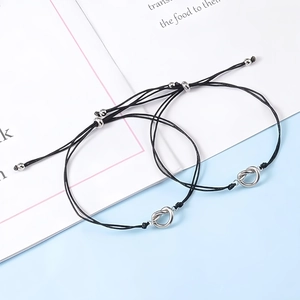 Detail of adjustable knotted friendship bracelets with silver metal knot charms on black cord