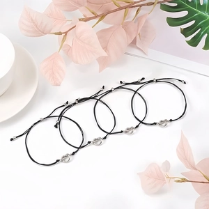 Close-up of four black woven knot bracelets with silver beads on a minimalist background