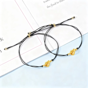 Close-up of black braided friendship bracelets with golden knot and adjustable slider
