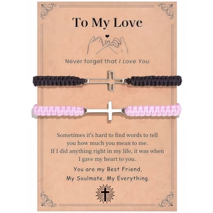 Close-up of woven couple bracelets with silver cross charms on gift message card