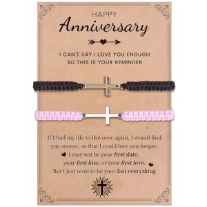 Detailed view of woven couple bracelets with silver cross charms on a gift message card