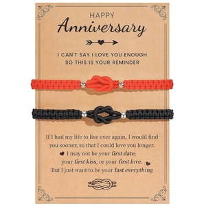 Detail von roten und schwarzen Knoten-Armbändern für Paare auf einer Jubiläums-Geschenkkarte
