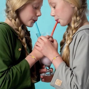 Close-up of minimalist black braided rope bracelets with gold charms for best friends