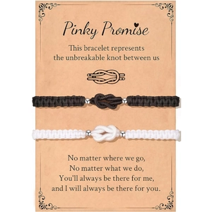 Detail der handgewebten Unendlichkeit-Pärchen-Armbänder in Schwarz und Weiß auf einer Karte