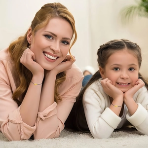 Close-up of mother and daughter wearing matching gold heart knot woven rope bracelets