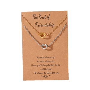 Friendship knot pendant necklaces in gold and silver finish on a brown gift card
