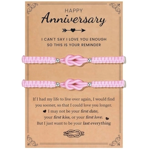 Rosa Paar-Armbänder mit konzentrischem Knoten auf einer Happy Anniversary-Geschenkkarte