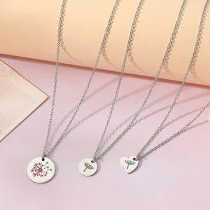 Détail de colliers en acier argenté avec pendentifs ronds et en forme de cœur à pissenlit