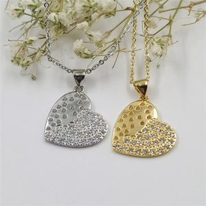 Macro shot of silver and gold layered heart pendants with cubic zirconia and sun motif