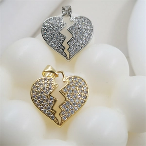 Detail of gold and silver broken heart pendants with white cubic zirconia pavé