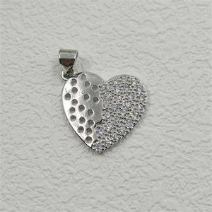 Macro detail of heart pendant showing polished silver metal and zircon pavé setting