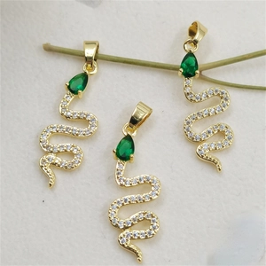 Detailed view of three gold snake pendants with green teardrop stones and white zircons