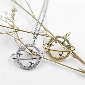 Makroaufnahme von Saturn-Anhängern in Gold und Silber mit Zirkonia-Kristallen und Sternen
