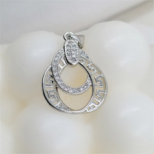 Macro shot of silver interlocking rings pendant with zircon inlay and Greek fret pattern