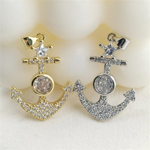Dettaglio dei pendenti ad ancora in oro e argento con micro-pave di zirconi e stelle