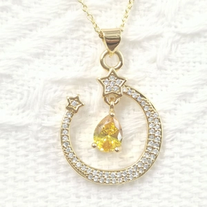 Star and moon necklace featuring a yellow pear-shaped stone in a gold setting