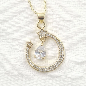 Macro detail of gold-plated moon and star necklace pendant with sparkling zircon stones