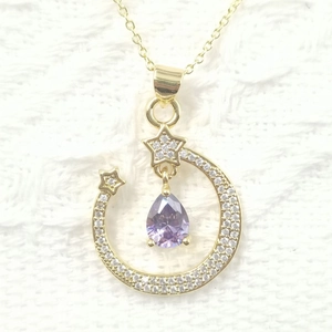 Detail of gold moon and star pendant necklace featuring purple teardrop gem and zircons