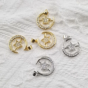Star and moon pendants with cubic zirconia in gold and silver finish on white fabric