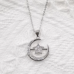 Macro shot of sparkling zircon moon and star pendant necklace on white velvet