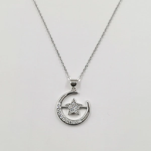 Macro shot of silver crescent moon and star pendant necklace set with sparkling zircons