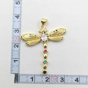 Top view of gold dragonfly pendant with colorful crystals and measurement scale