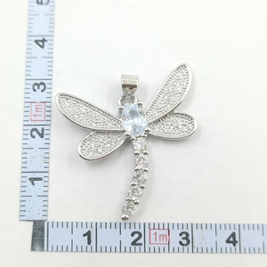Macro view of silver dragonfly pendant with zircon pave and central oval stone