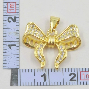 Macro shot of gold-plated bow necklace pendant with zircon micro-paving and size measurement