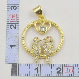 Macro detail of bird pendant with white zircons and clear gemstone showing 3cm size scale