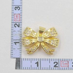 Detailed view of gold bow pendant with sparkling zircons measured with an L-scale ruler