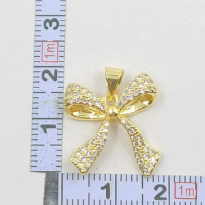 Detail view of gold-plated bow necklace pendant with zircon pavé and measuring tape