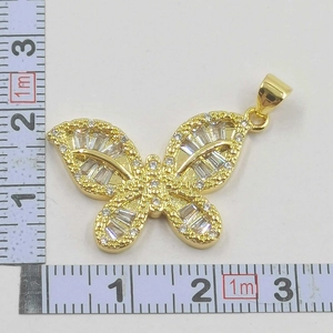 Macro detail of gold bow pendant with zircon stones showing exact measurements
