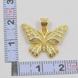 Macro detail of a hollow gold butterfly pendant with sparkling cubic zirconia inlay