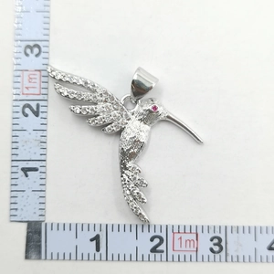 Macro view of crystal hummingbird pendant showing dimensions with measuring tape
