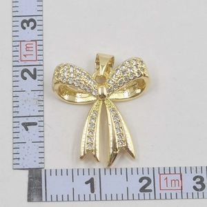 Size measurement of a gold bow pendant with cubic zirconia stones showing 2.5cm width