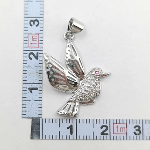 Macro view of crystal-encrusted hummingbird pendant with measurement scale