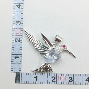 Detail shot of a crystal hummingbird pendant in silver finish with precise measurements