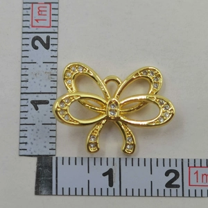 Bow necklace pendant in gold plating with zircon stones shown next to a ruler for size