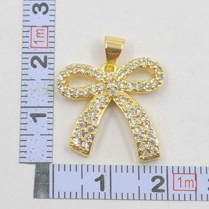 Close-up of a gold-plated bow necklace pendant with sparkling zircon inlays and scale